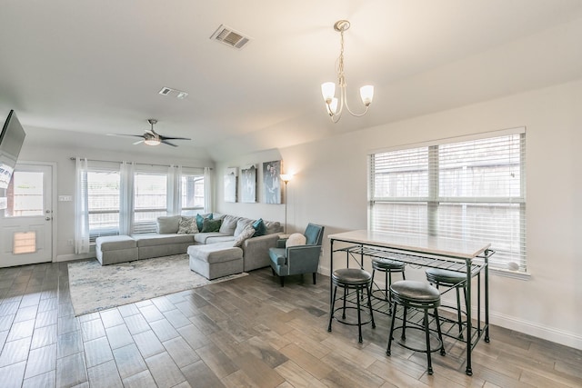 living area with ceiling fan with notable chandelier, baseboards, wood finished floors, and visible vents