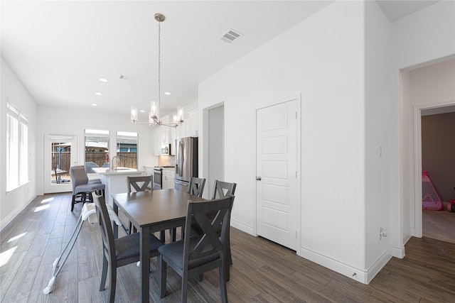 dining space with an inviting chandelier, dark wood finished floors, baseboards, and visible vents
