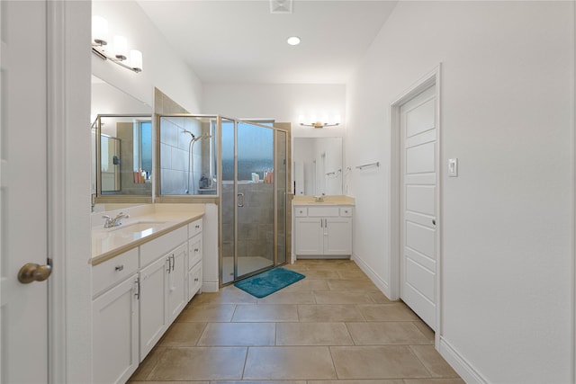 full bath with baseboards, two vanities, a sink, a stall shower, and tile patterned flooring