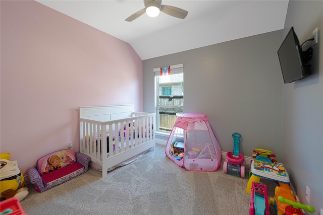 bedroom with vaulted ceiling, a crib, carpet flooring, and a ceiling fan