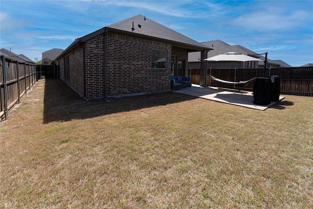 exterior space featuring a fenced backyard, a patio, brick siding, and a yard