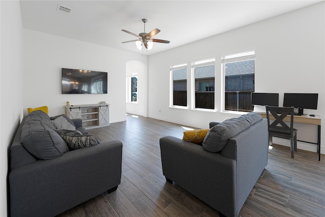 living area featuring visible vents, baseboards, ceiling fan, dark wood finished floors, and arched walkways