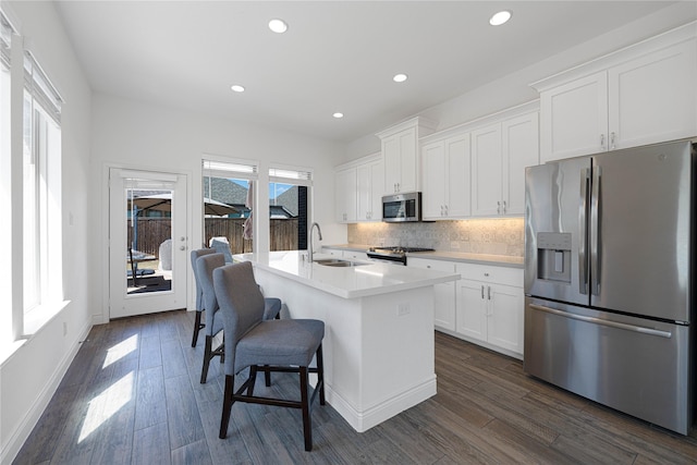 kitchen with dark wood-style floors, white cabinetry, decorative backsplash, and stainless steel appliances