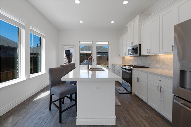kitchen featuring a sink, tasteful backsplash, appliances with stainless steel finishes, and dark wood-type flooring