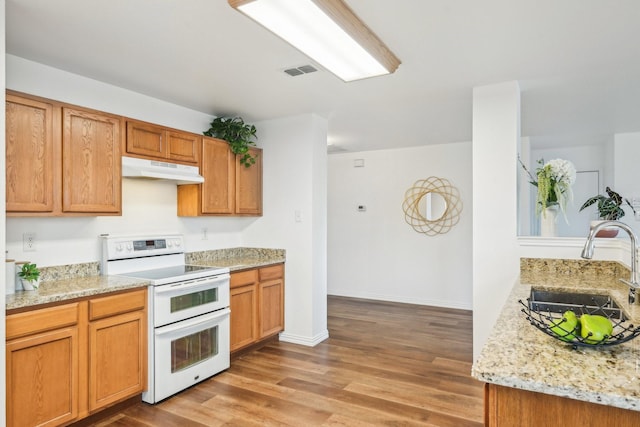 2905 Meadow Bluff Dr, Wylie, TX 75098 - kitchen featuring range with two ovens, a sink, under cabinet range hood, light wood-type flooring, and light stone counters