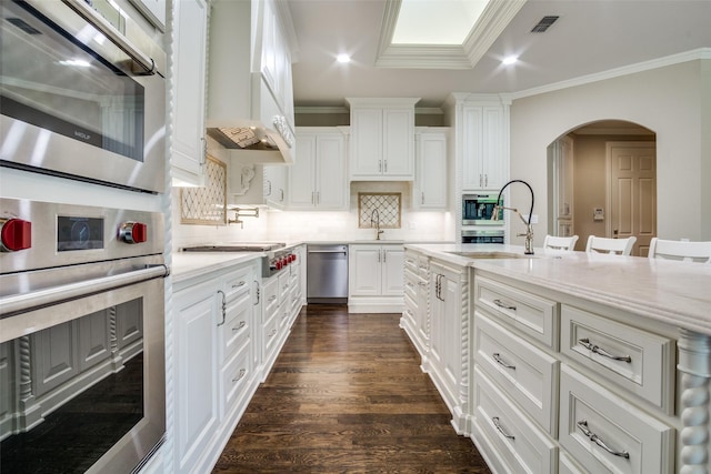 5816 Forest Highlands Dr, Fort Worth, TX 76132 - kitchen with stainless steel appliances, premium range hood, arched walkways, white cabinetry, and dark wood-style floors