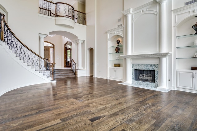 5816 Forest Highlands Dr, Fort Worth, TX 76132 - unfurnished living room featuring stairway, built in shelves, wood finished floors, arched walkways, and ornate columns