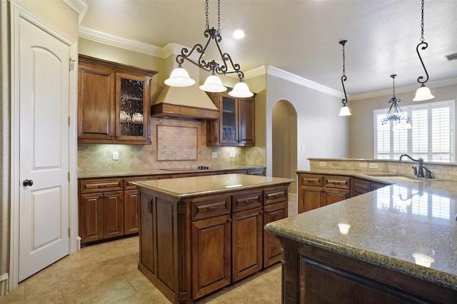 1304 Rollie Michael Ln, Fort Worth, TX 76179 - kitchen featuring ornamental molding, a center island, arched walkways, a sink, and backsplash