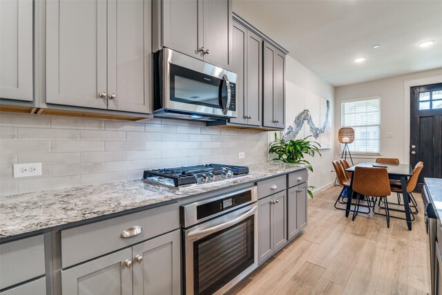 6510 Baritone Ct, Sachse, TX 75048 - kitchen featuring stainless steel appliances, gray cabinetry, light wood-style flooring, baseboards, and backsplash