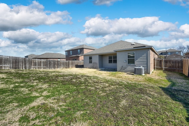 rear view of house with a fenced backyard, cooling unit, and a lawn
