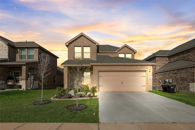 traditional-style home featuring driveway, roof with shingles, an attached garage, a lawn, and brick siding