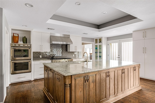 5230 Boca Raton Dr, Dallas, TX 75229 - kitchen featuring wall chimney range hood, stainless steel double oven, a tray ceiling, and visible vents