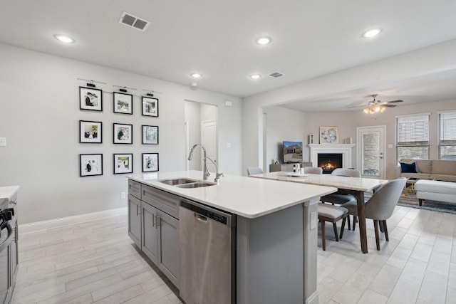 1702 Gallant Fox Dr, Rockwall, TX 75032 - kitchen with stainless steel dishwasher, a sink, gray cabinetry, a lit fireplace, and light countertops