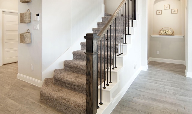 stairs with baseboards, arched walkways, and wood finished floors