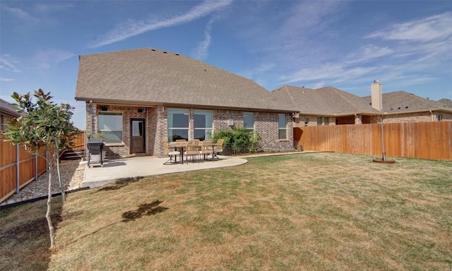 back of house with a fenced backyard, brick siding, a shingled roof, a yard, and a patio area