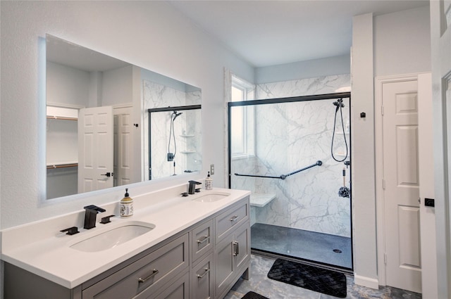 bathroom with double vanity, a sink, and a marble finish shower