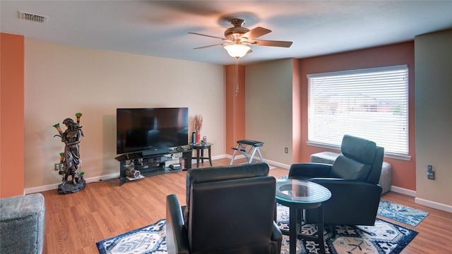 living room featuring wood finished floors, a wealth of natural light, ceiling fan, and visible vents