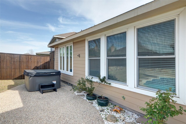 exterior space featuring a hot tub, fence, and a patio area