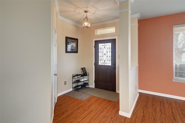 foyer entrance featuring baseboards, ornate columns, wood finished floors, and crown molding