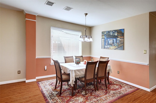 dining area with baseboards, visible vents, an inviting chandelier, and wood finished floors