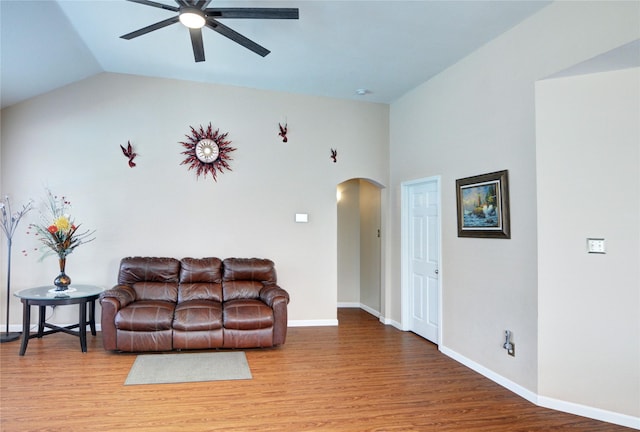 living room with vaulted ceiling, a ceiling fan, wood finished floors, baseboards, and arched walkways