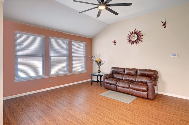 living area featuring baseboards, wood finished floors, vaulted ceiling, and a ceiling fan
