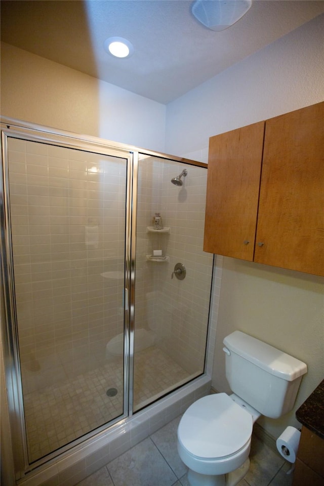 bathroom featuring a shower stall, toilet, and tile patterned floors