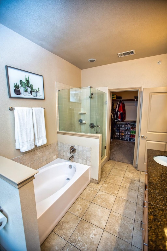 bathroom featuring a spacious closet, tile patterned floors, visible vents, a garden tub, and a stall shower
