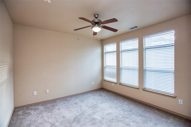 unfurnished room with ceiling fan, baseboards, carpet flooring, and visible vents