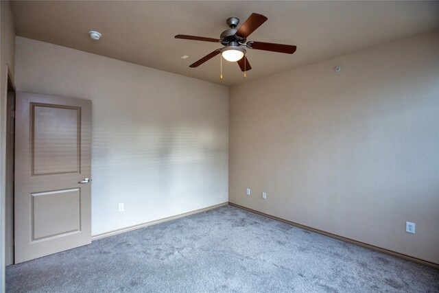 carpeted empty room featuring baseboards and a ceiling fan