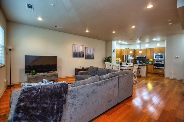 living room with recessed lighting, wood finished floors, and visible vents