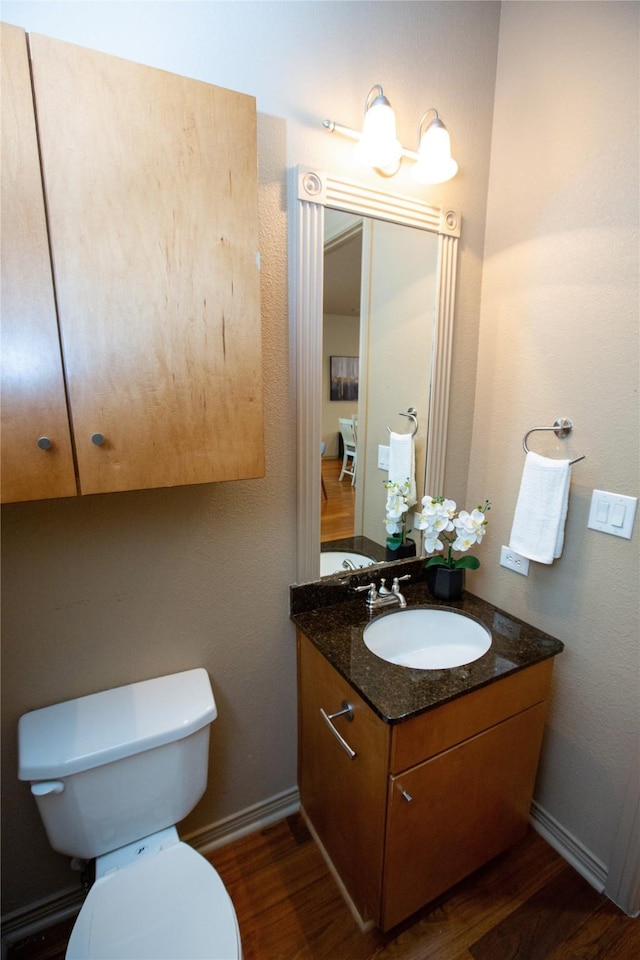 bathroom with baseboards, wood finished floors, vanity, and toilet