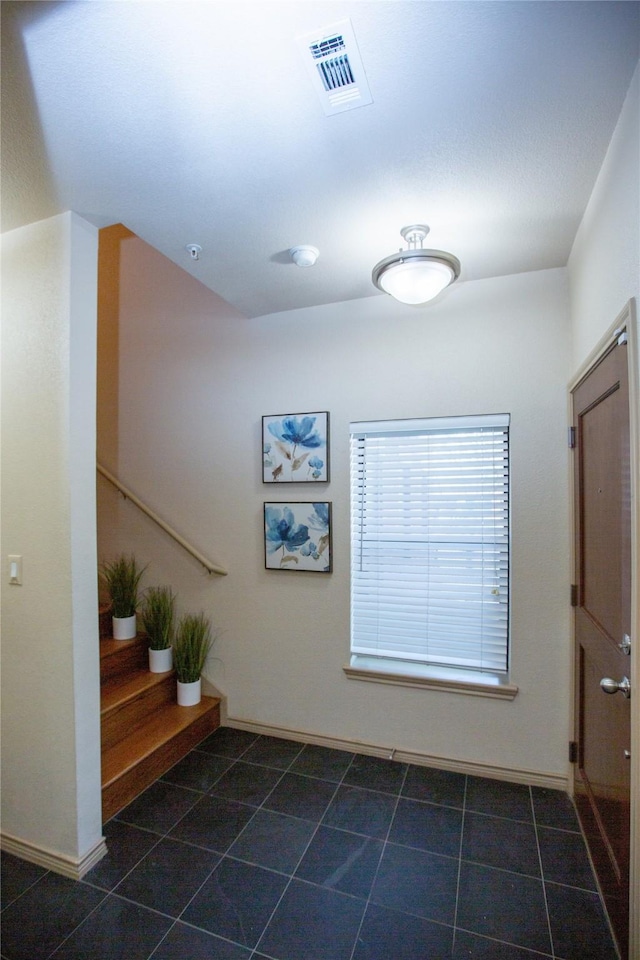 hallway featuring baseboards, tile patterned floors, stairs, and visible vents