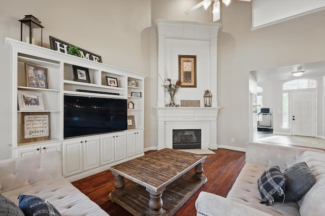 820 Clearlake Dr, Prosper, TX 75078 - living room with dark wood-style floors, ceiling fan, a large fireplace, a high ceiling, and baseboards