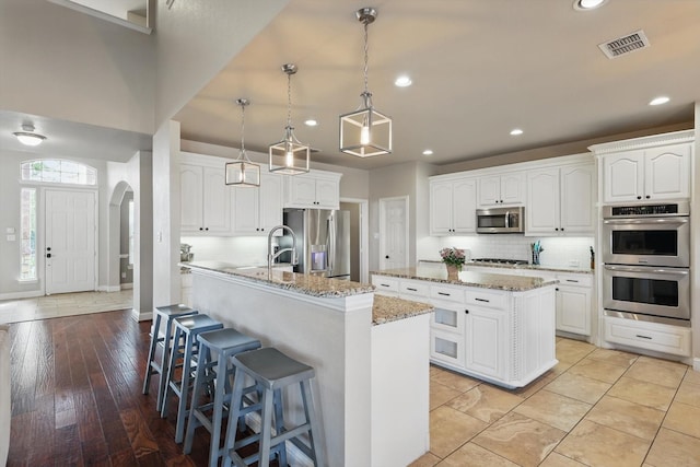 820 Clearlake Dr, Prosper, TX 75078 - kitchen featuring a kitchen island with sink, stainless steel appliances, backsplash, white cabinets, and recessed lighting
