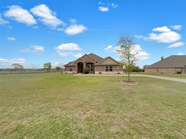 view of front of property with brick siding, fence, concrete driveway, and a front yard