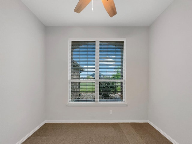 carpeted spare room featuring baseboards and a ceiling fan
