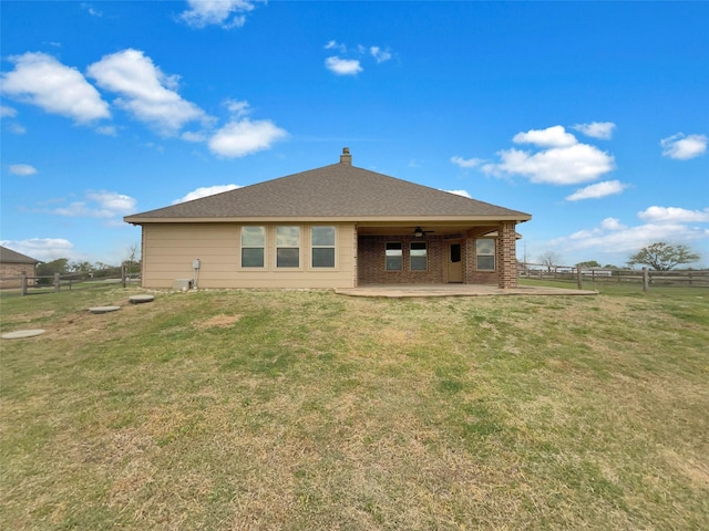 back of house with fence, a chimney, a ceiling fan, a yard, and a patio area