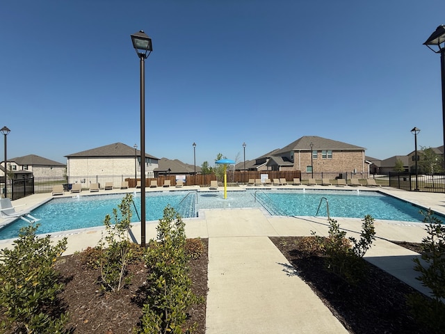 pool featuring fence, a patio area, and a residential view
