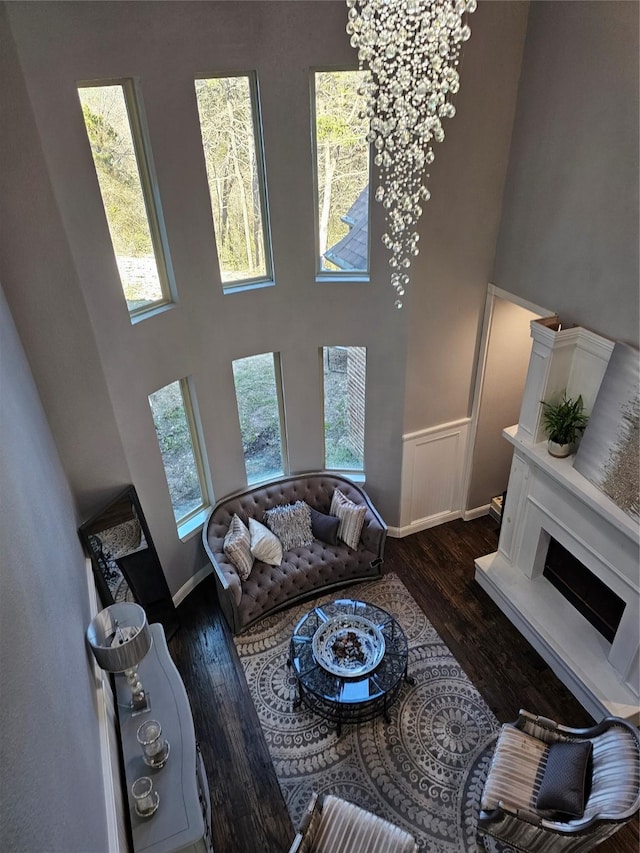 living room featuring wood finished floors, a high ceiling, baseboards, and an inviting chandelier