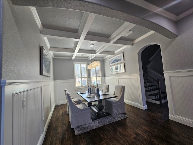 dining area with stairway, wood finished floors, arched walkways, a wainscoted wall, and beam ceiling