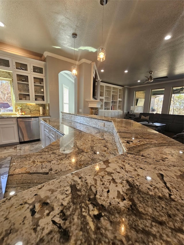 kitchen featuring light stone counters, dishwasher, arched walkways, a textured ceiling, and ceiling fan