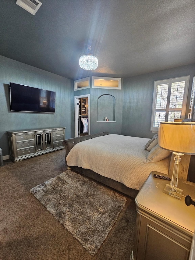 bedroom featuring a notable chandelier, carpet flooring, a textured ceiling, and visible vents