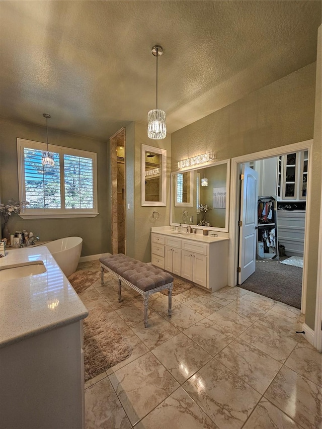 bathroom with a notable chandelier, vanity, and a textured ceiling