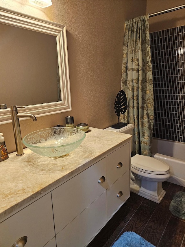 full bathroom featuring toilet, a textured wall, vanity, and shower / tub combo with curtain