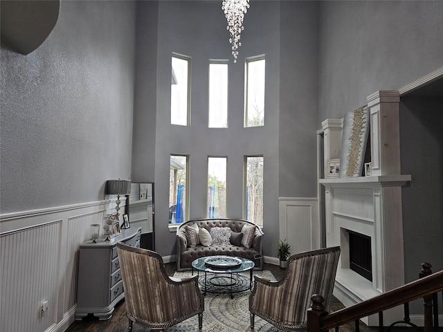 living room featuring plenty of natural light, a high ceiling, a fireplace, and dark wood-style flooring