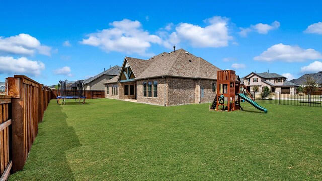 1651 Wynne Ave, Prosper, TX 75078 - rear view of property featuring a trampoline, a playground, brick siding, and a residential view