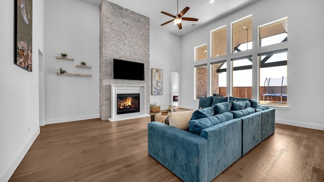 1651 Wynne Ave, Prosper, TX 75078 - living room with ceiling fan, a fireplace, wood finished floors, a high ceiling, and baseboards