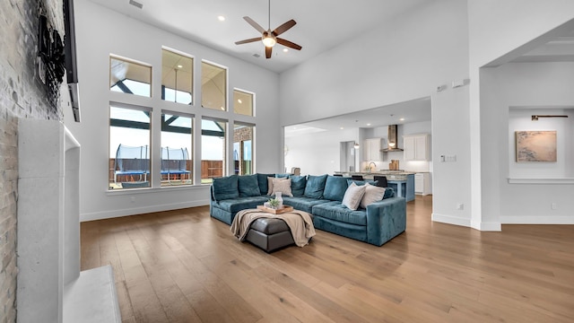 1651 Wynne Ave, Prosper, TX 75078 - living area featuring a ceiling fan, light wood-style flooring, a towering ceiling, baseboards, and recessed lighting