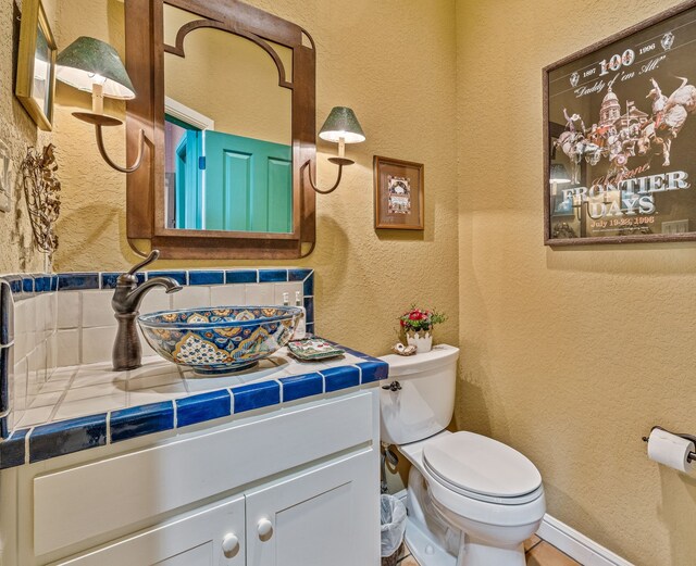 4204 Bluff View Dr, Granbury, TX 76048 - half bathroom featuring a textured wall, toilet, backsplash, and vanity